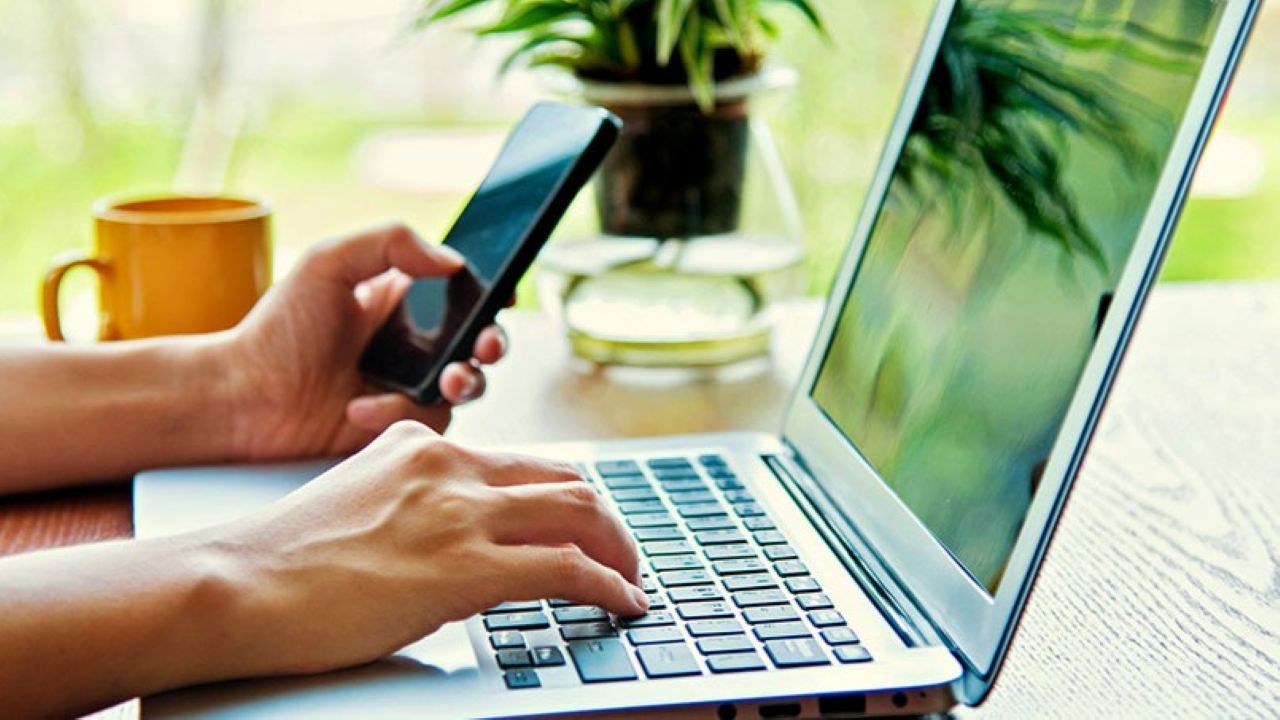 persona usa computer con smartphone